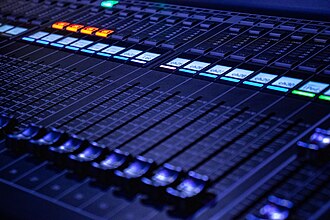 Faders et commandes éclairées d’une console audio, photographiés en gros plan